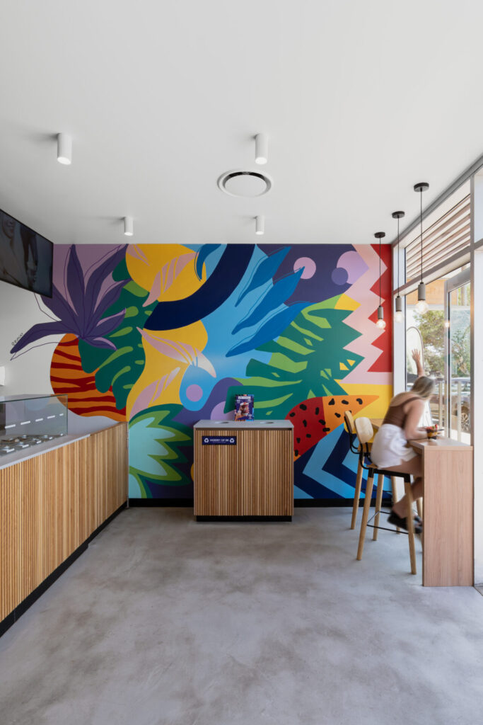 Custom colourful wall mural, bespoke wood counter panelling and welcoming dining area for this hospitality fit out for Oakberry Coolum