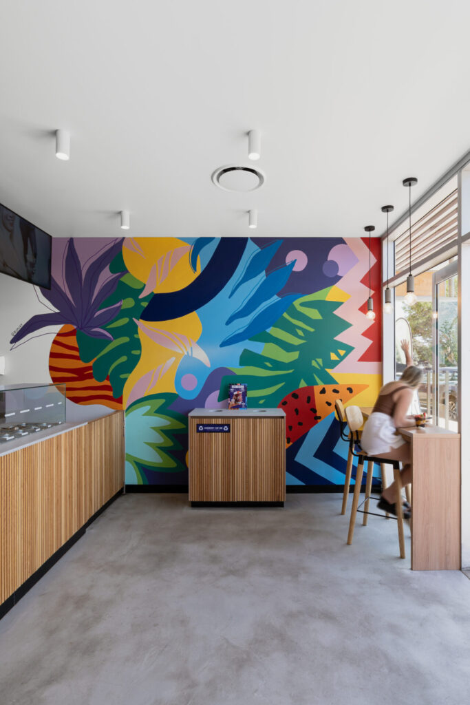 Custom colourful wall mural, bespoke wood counter panelling and welcoming dining area for this hospitality fit out for Oakberry Coolum