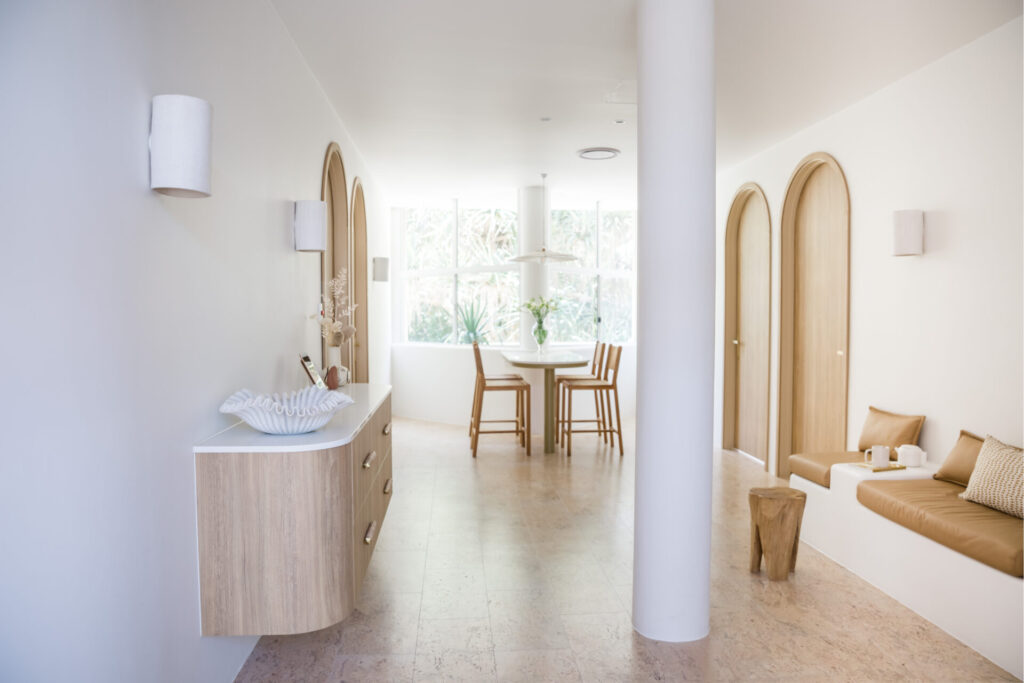 Floor to ceiling windows, curved bespoke wooden doors and welcoming reception area for this wellness & beauty fit out for The Heart of Beauty