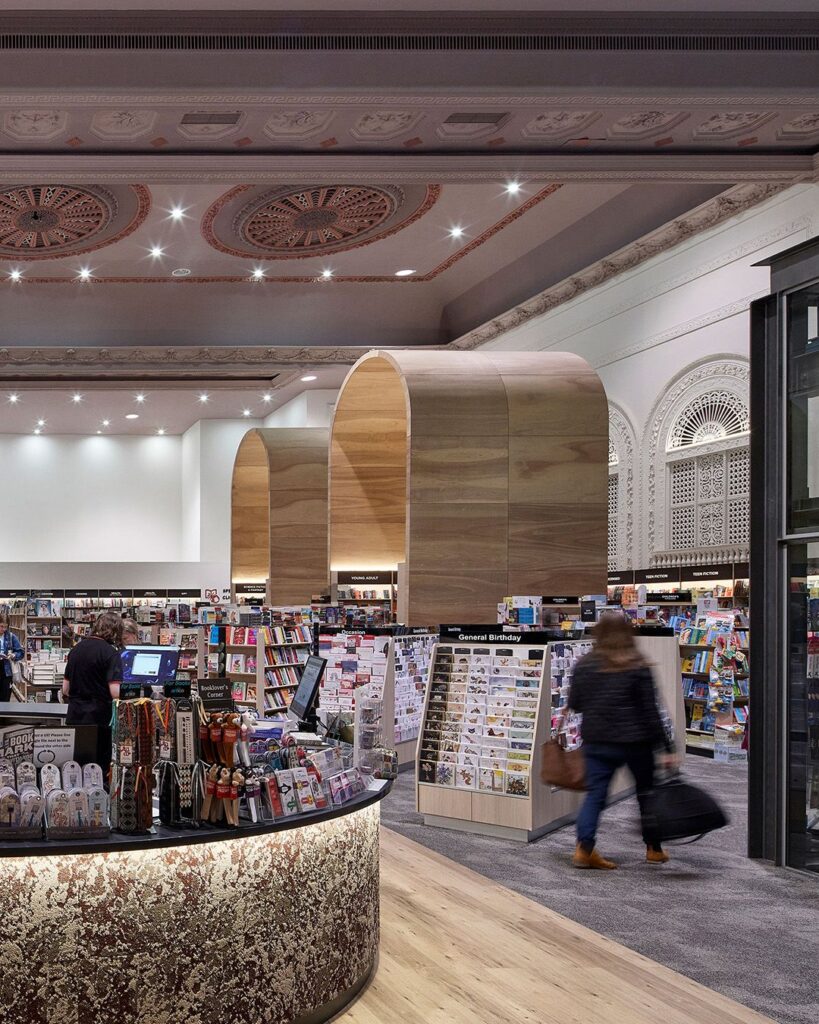 Bespoke wood arched book displays, hardwood and carpeted floors and heritage wall and ceiling features for this retail fit out for Dymocks