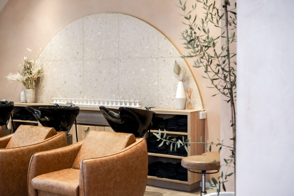 Rounded gold mirrors, neutral and brown colour palette and welcoming reception area for this wellness & beauty fit out for Blondee Salon