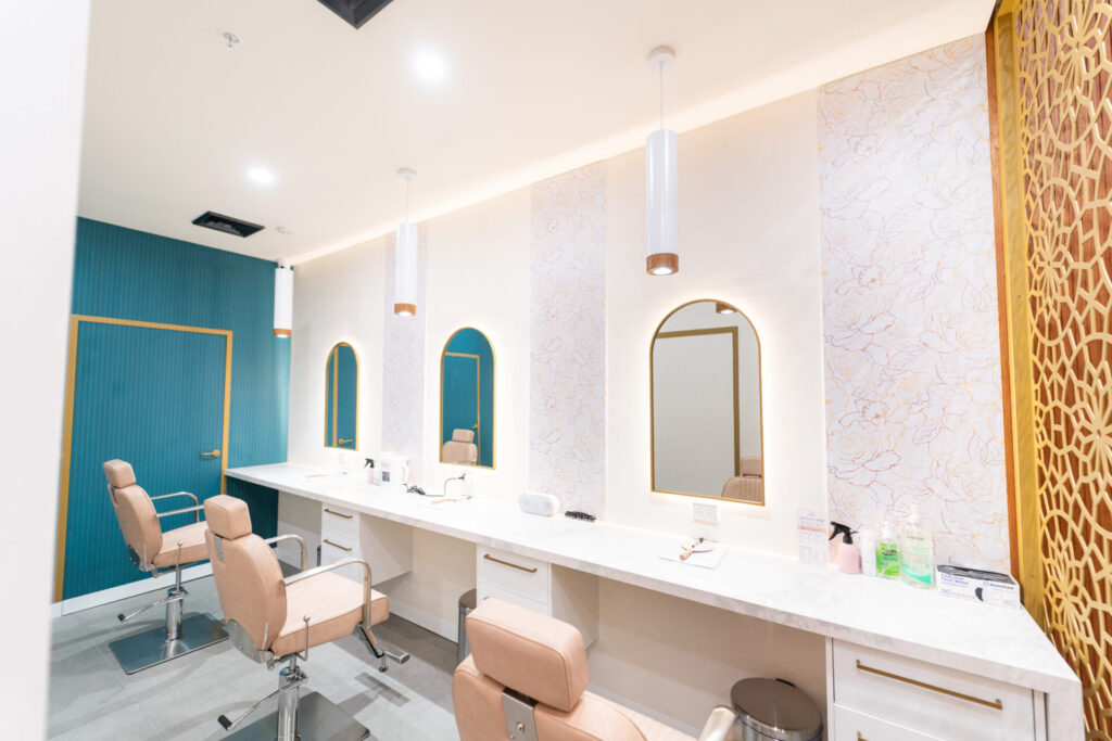 Light pink chairs, blue and gold colour palette with neutral splashbacks and welcoming reception area for this wellness & beauty fit out for Just Brows and Beauty