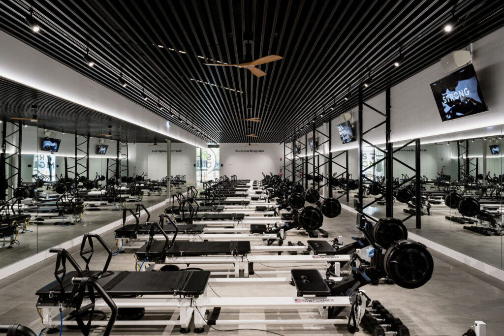 Pilates reformers, concrete floors and welcoming reception area for this fitness fit out for Strong Pilates