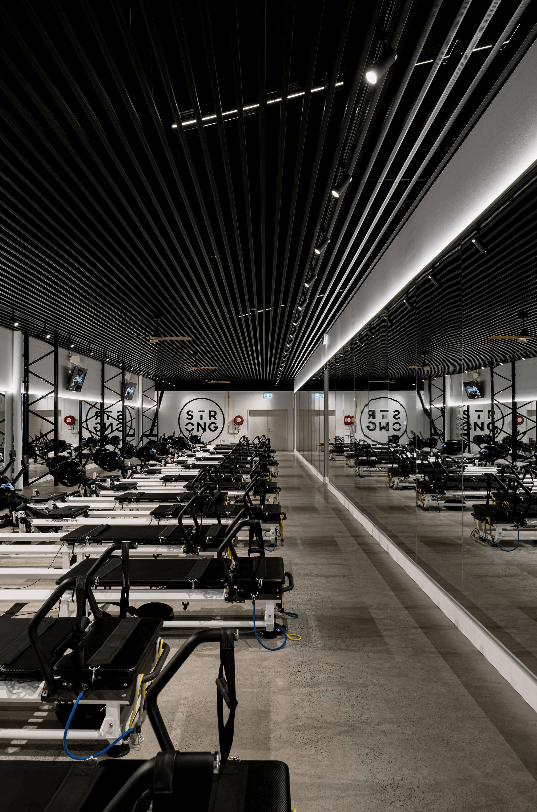 Open ceiling with black structuring, welcoming reception area and concrete flooring for this fitness fit out for Strong Pilates