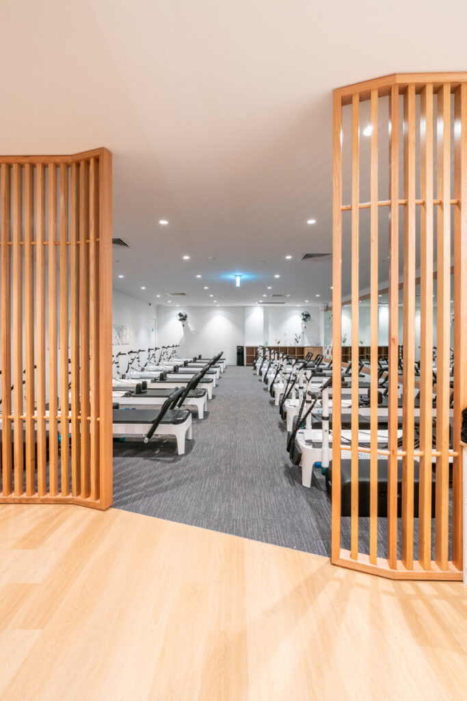 On brand colour palette, high end reformer beds and timber screen for this fitness fit out for KX Pilates