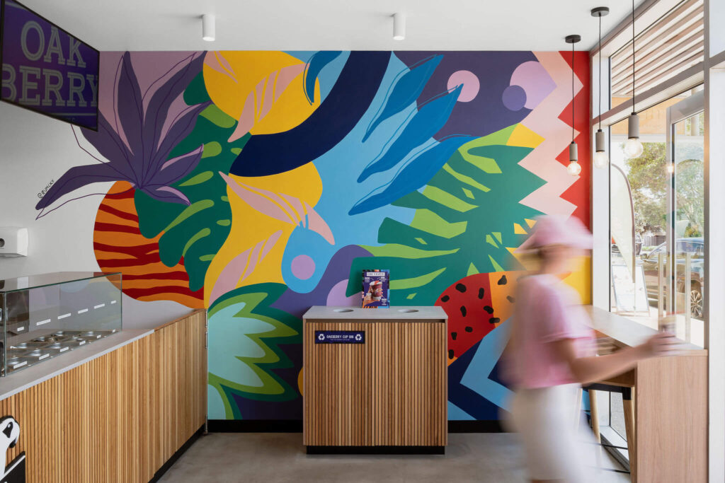 Colourful custom wall mural, concrete flooring and welcoming dining area for this hospitality fit out for Oakberry
