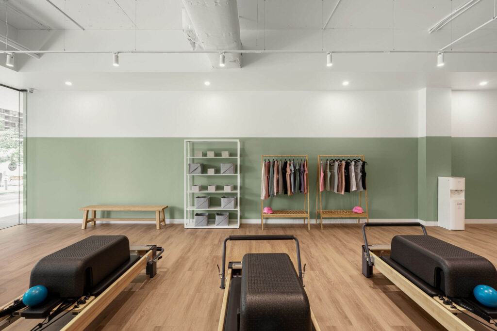 Earthy colour palette, wooden high end reformer beds and timber screen for this fitness fit out for Premium Pilates