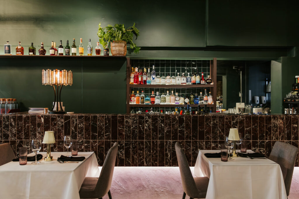 Curved bespoke timber glasses holder, deep green and brown colour palette and welcoming dining area for this hospitality fit out for Thai Room