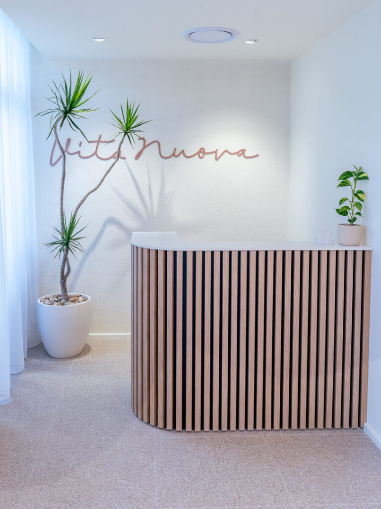 Curved LED lighting fitted around wall features, neutral colour palette and vj panelling reception counter for this wellness & beauty fit out for Vita Nuova