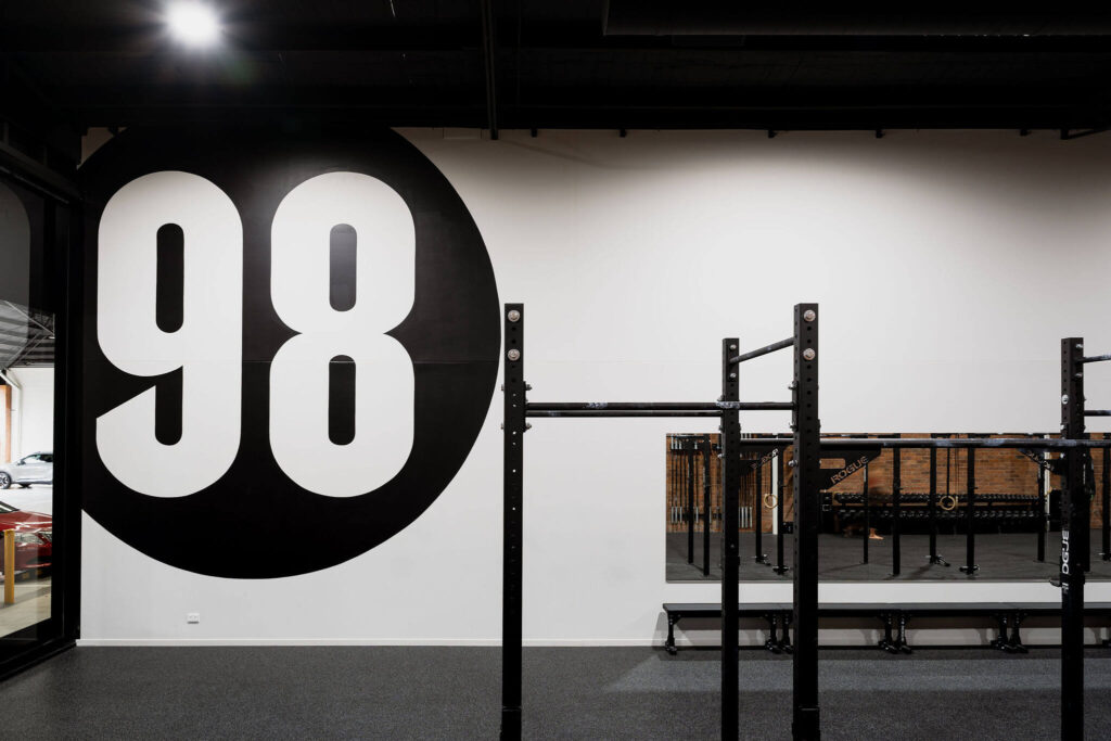 Black and white branded colour palette, high end black gym equipment and original brick feature wall for this commercial fitness fit out for 98 Gym