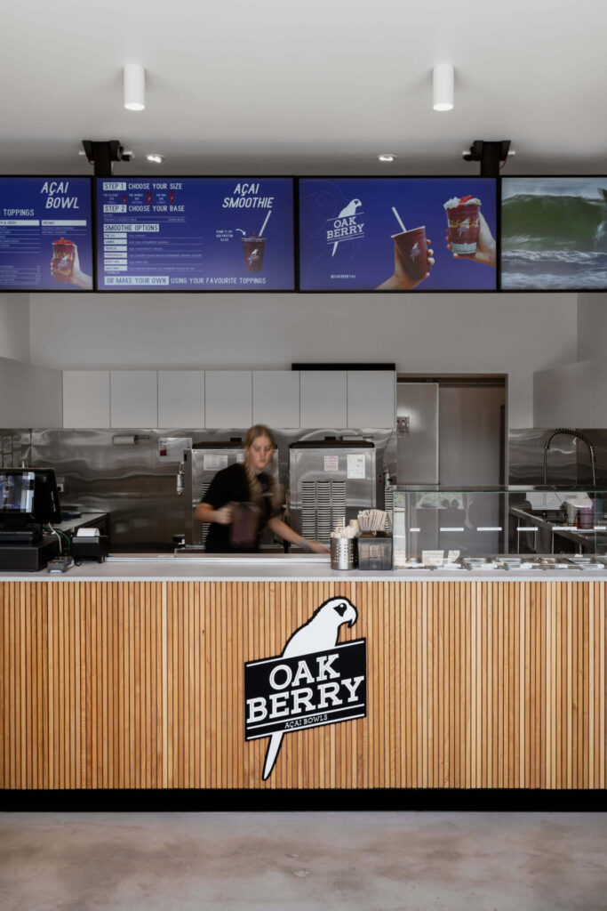 Timber vj panelling, custom on-brand signage and concrete flooring for high-foot traffic for this hospitality fit out for Oakberry Acai, Total Fitouts Sunshine Coast North
