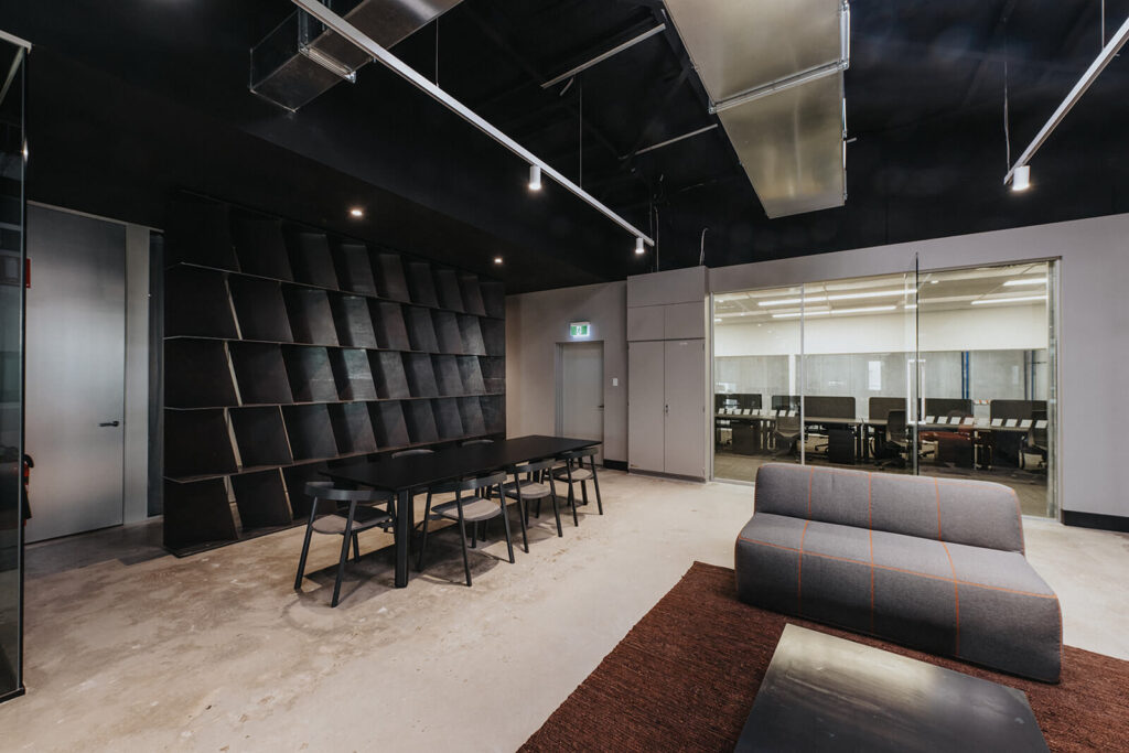 Mesh barrier ceilings, bold black and orange colour palette and striking reception area for this office fit out for Raubex