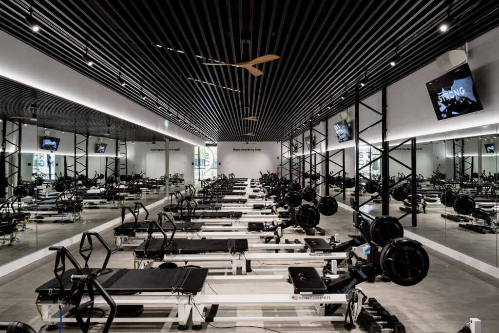 Black timber ceiling panelling, concrete flooring and on brand black and white colour palette for this fitness fit out for Strong Pilates West End, Total Fitouts Brisbane Inner South