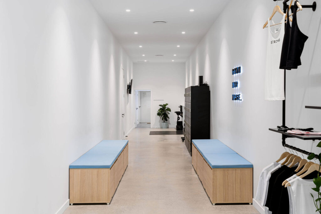 Blue with black accented branded colour palette, high end pilates equipment and elegant black merchandise display for this commercial fitness fit out for Strong Pilates West End