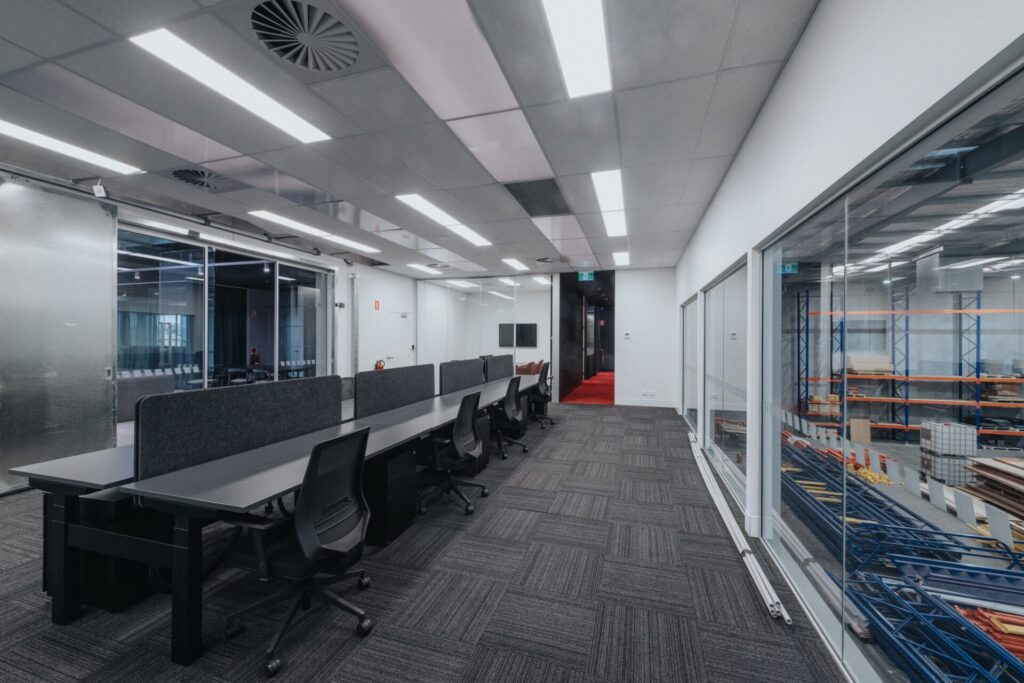 Mesh barrier ceilings, bold black and orange colour palette and striking reception area for this office fit out for Raubex