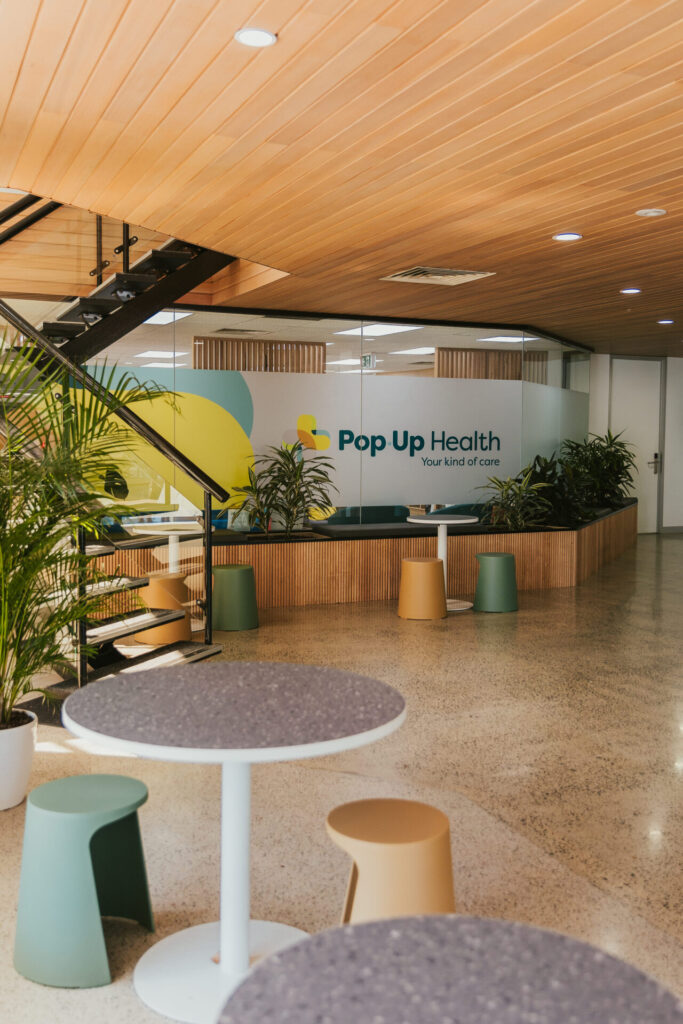 Custom branded signage, timber wall and ceiling panelling and vibrant colour palette for this medical fit out for Pop Up Health, Total Fitouts Adelaide Central